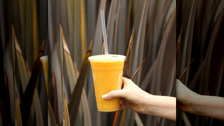 hand holding orange passionfruit smoothie