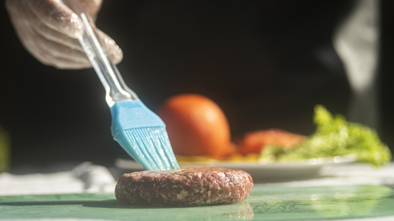 Hand brushing butter on burger