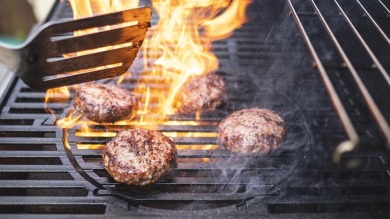 Burgers cooking on flaming grill