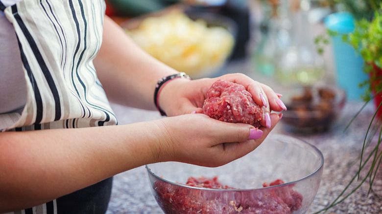 woman forming hamburger patties from raw meat