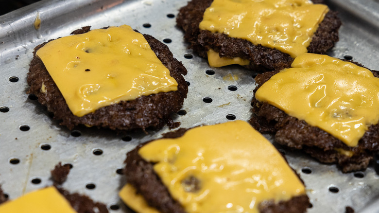 Melted cheese on cooked hamburger patties