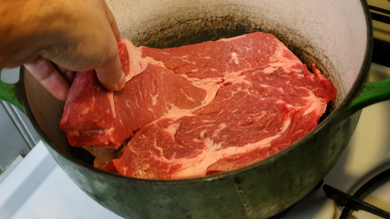 placing chuck roast in pot