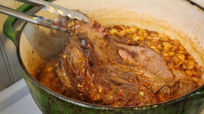 placing chuck roast in barbacoa pot