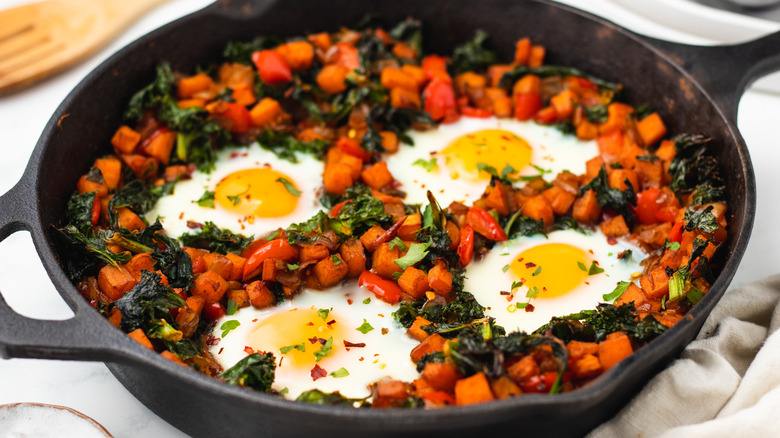 Sweet potato kale hash with eggs in skillet