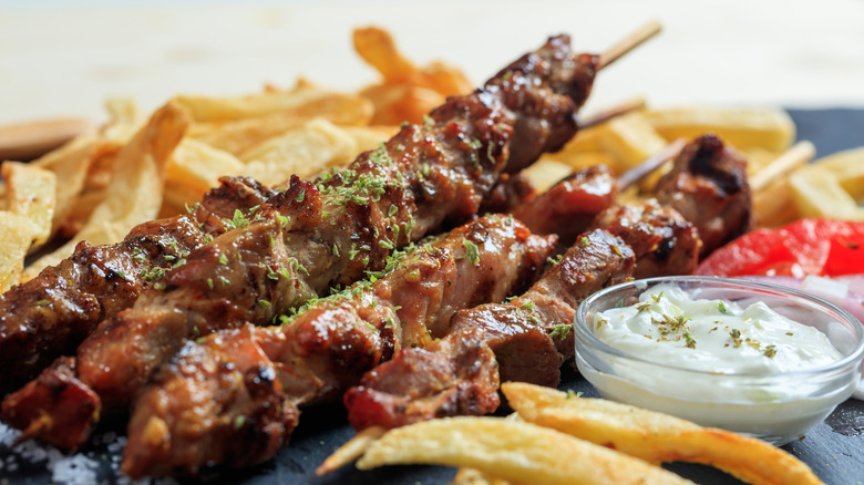 Grilled meat skewers, Greek souvlaki, and fried potatoes