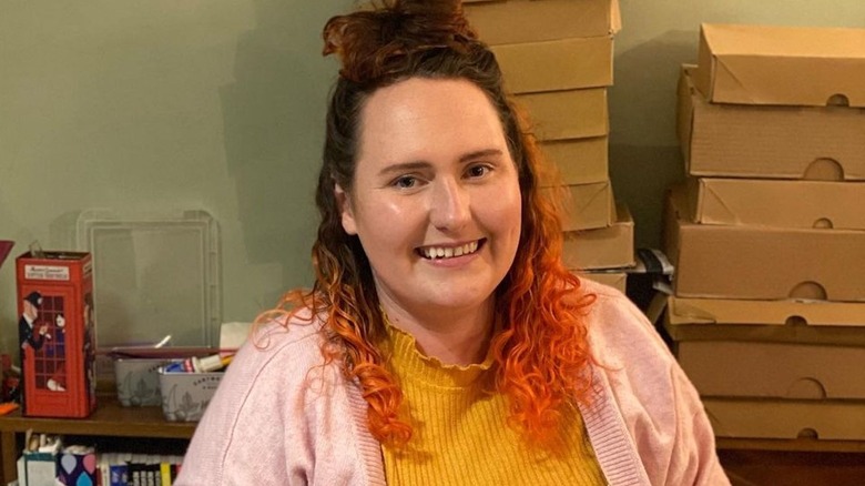 Lizzie Acker from GBBO with orange hair and yellow shirt