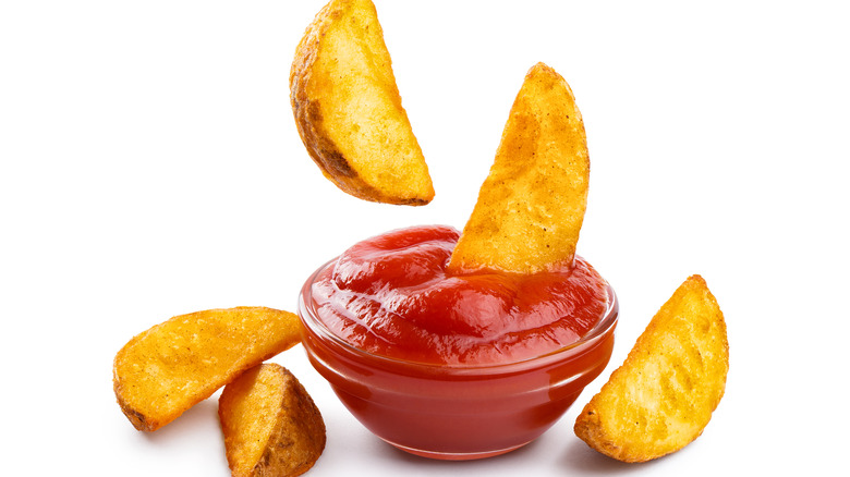 Potato wedges dipped in ketchup