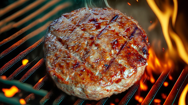 Burger patty on grill over flames