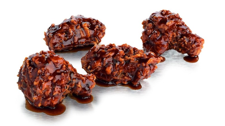 Pieces of sauced fried chicken on white background