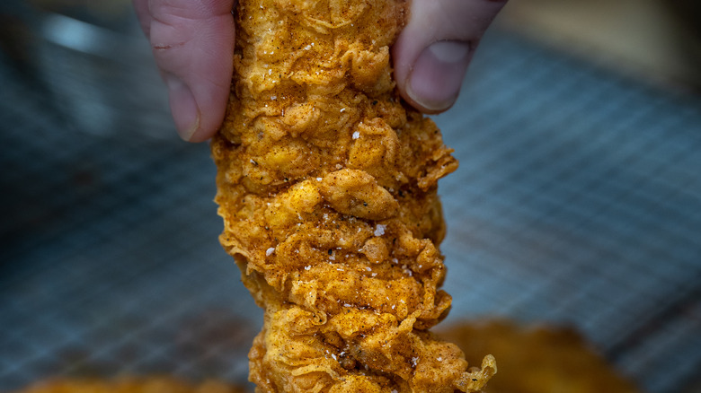 Person lifting a chicken tender 