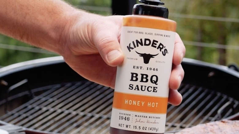 Kinder's sauce bottle held over grill