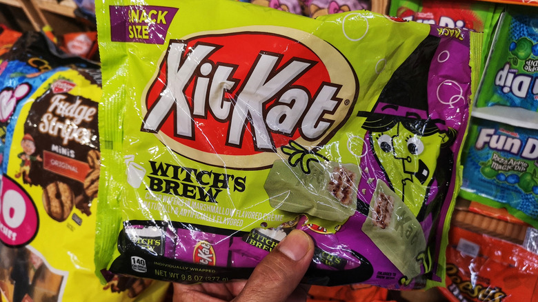 A hand holds a bag of Kit Kat Witch's Brew Halloween bars