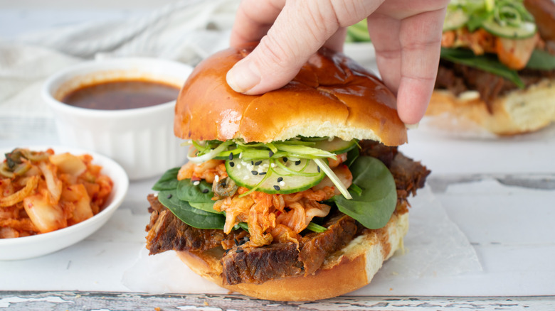 adding top bun to bulgogi bbq brisket sandwich