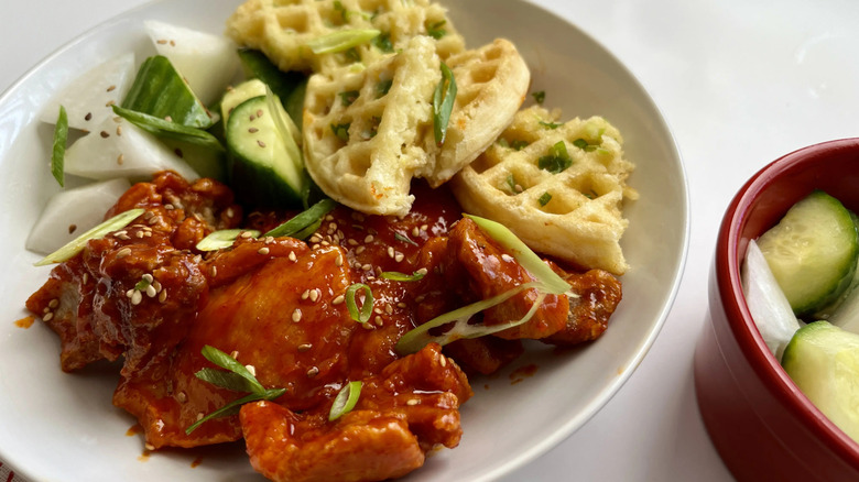 Korean fried chicken, vegetables, and waffles on plate