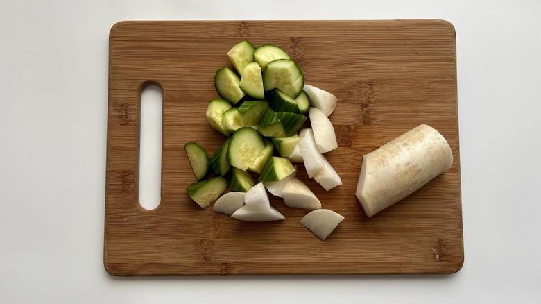 Sliced cucumber and radish on cutting board