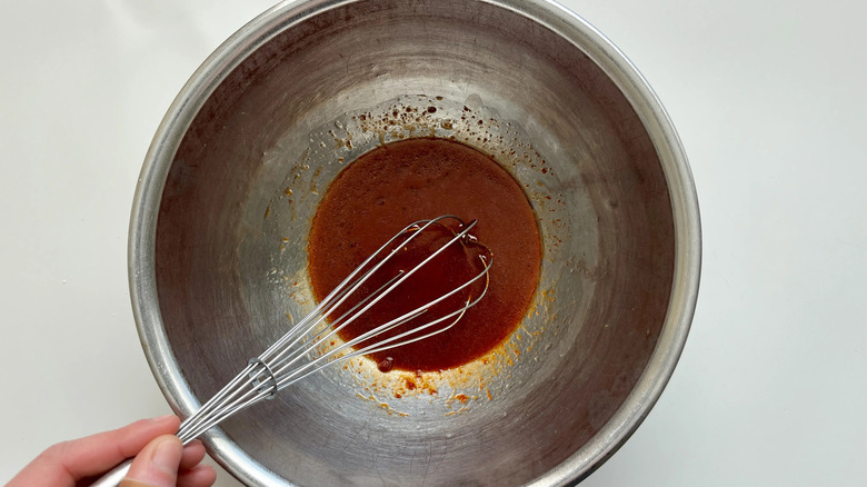 Hand whisking gochujang sauce in bowl