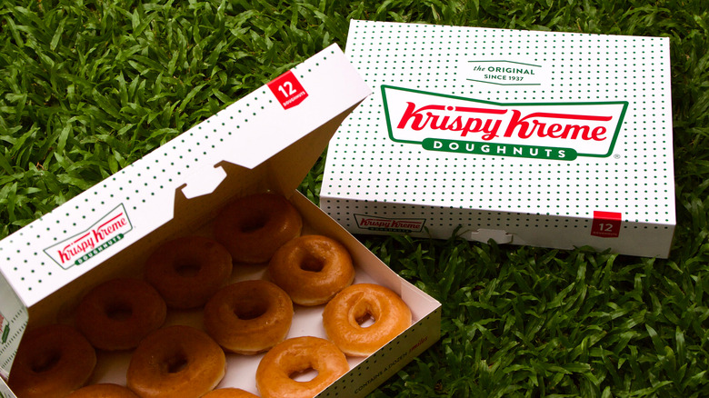 Two boxes of Krispy Kreme donuts on the grass