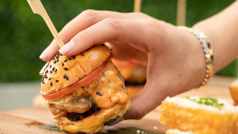 Hand holding cheeseburger slider