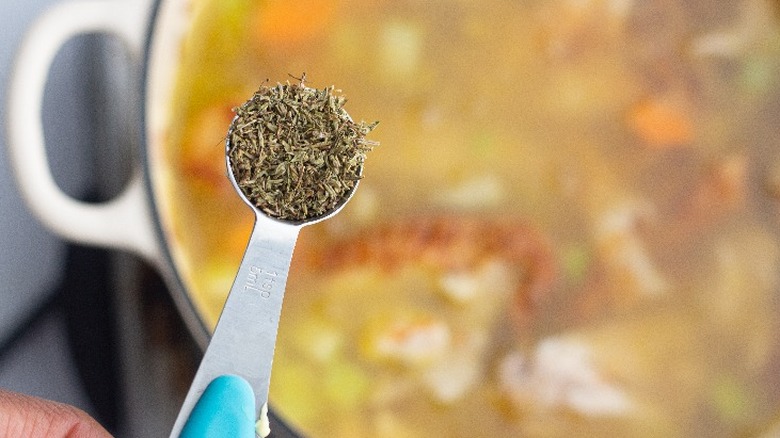 adding spices to chicken soup