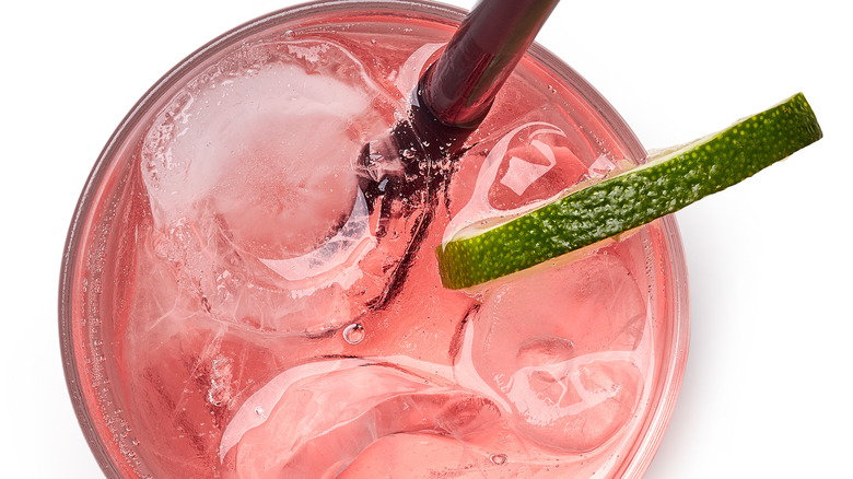 Pink lemonade in a glass with a straw and lime slice