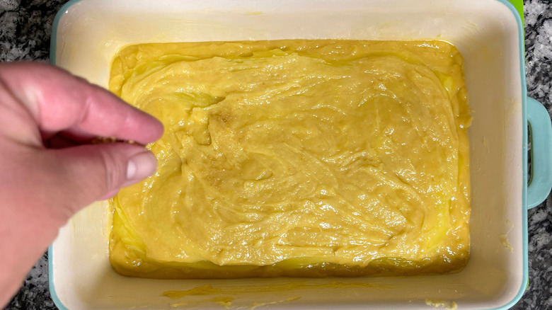 Hand sprinkling sugar onto unbaked cake