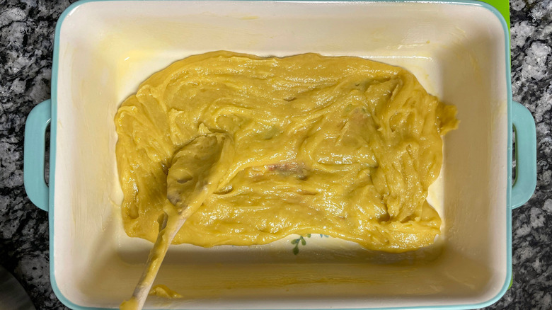 Wooden spoon spreading cake batter into baking dish