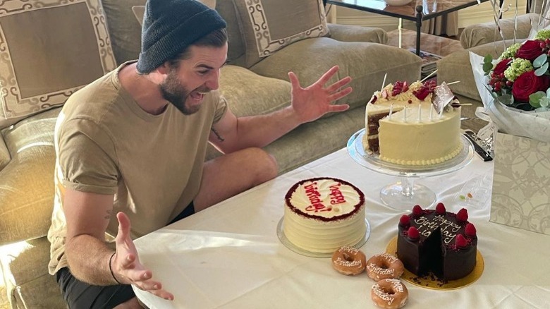 Liam Hemsworth posing with birthday cakes