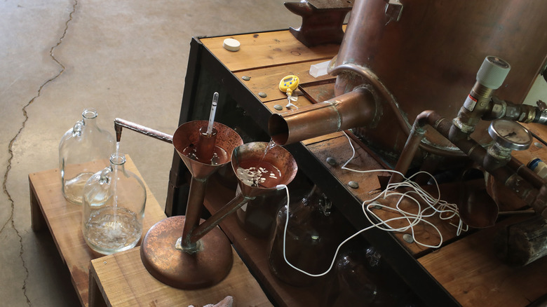 Bottles of moonshine being filled from a still