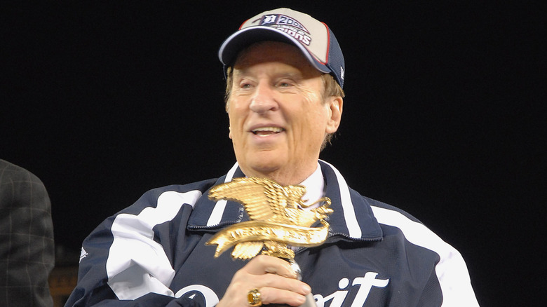 Little Caesars founder Mike Ilitch holding trophy