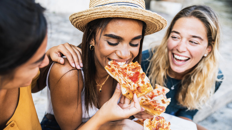 young women friends eating pizza