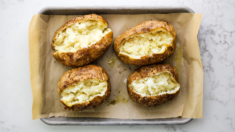 fluffed baked potatoes cut open on baking dish