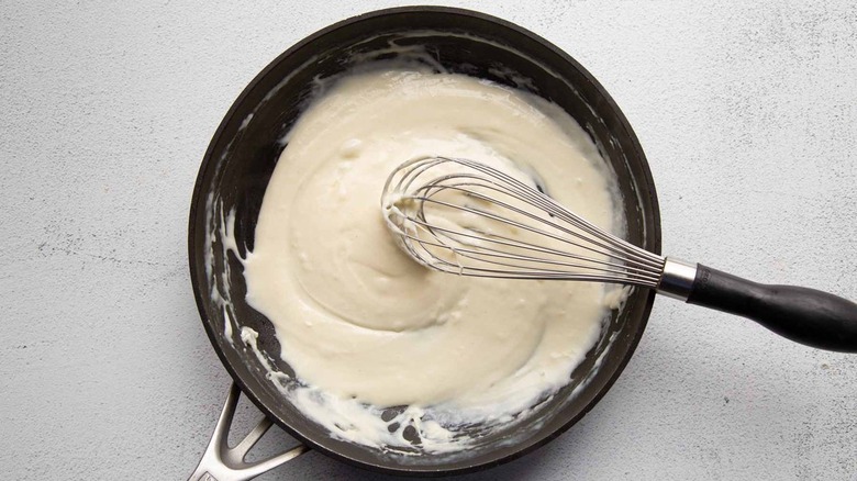 white sauce in frying pan with whisk