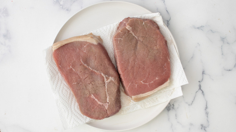 raw steaks on plate