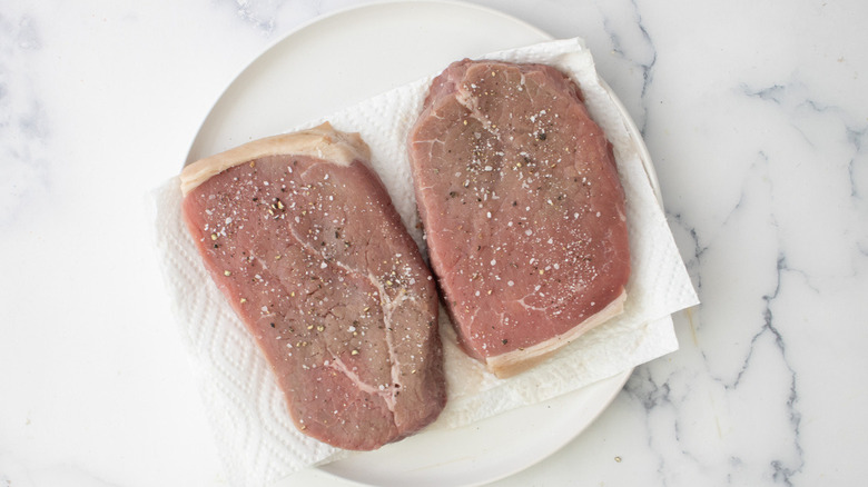 raw steaks with salt and pepper