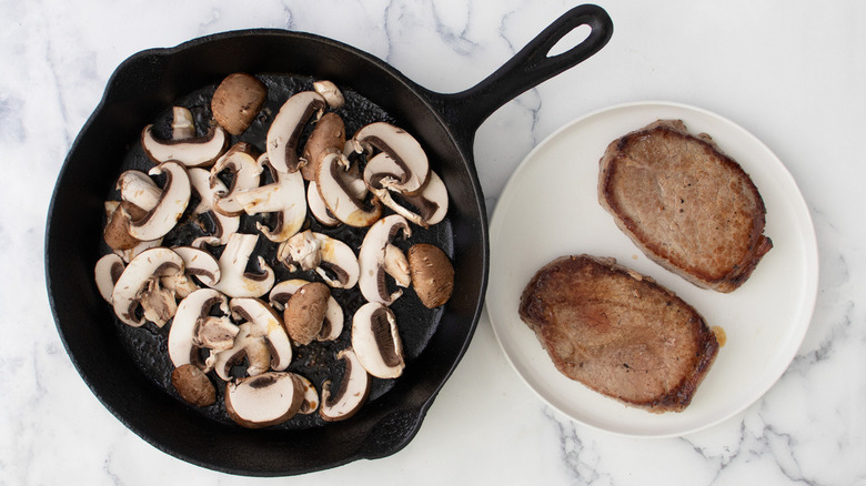 mushrooms in skillet next to steaks