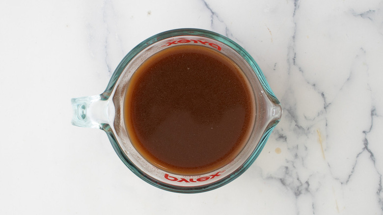 dark brothy sauce in measuring cup