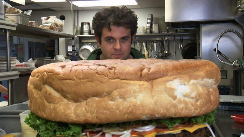 Adam Richman peeking over ridiculously large burger