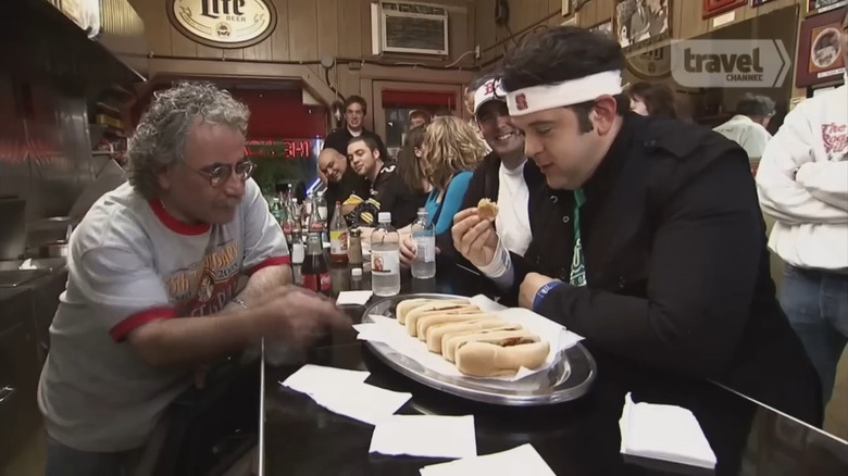 Adam Richman at table eating chili dogs