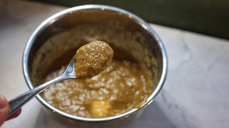 spoon of mango barbecue sauce above bowl