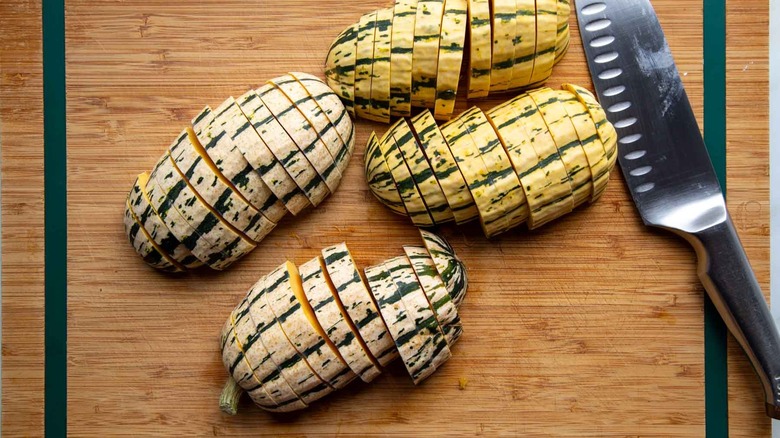 sliced delicata squash on cutting board with knife