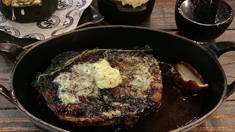 Close up of a butter-topped steak in a cast iron pan