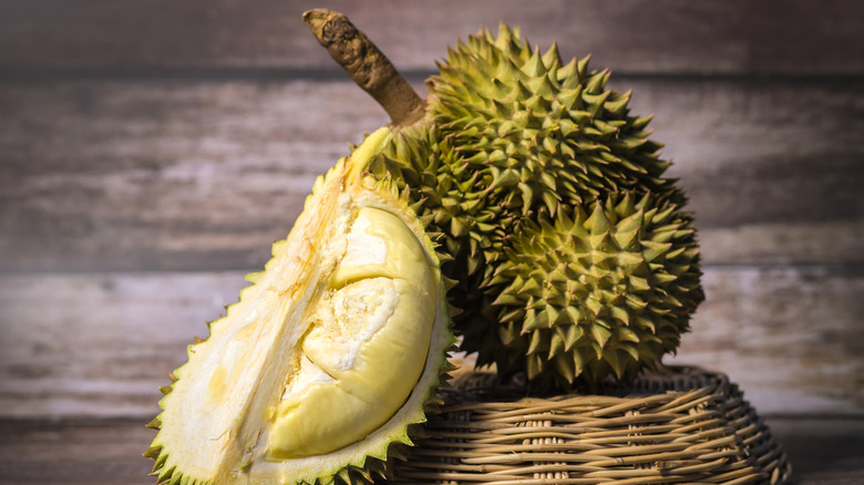 Durian fruit whole and cut in half on a dark background