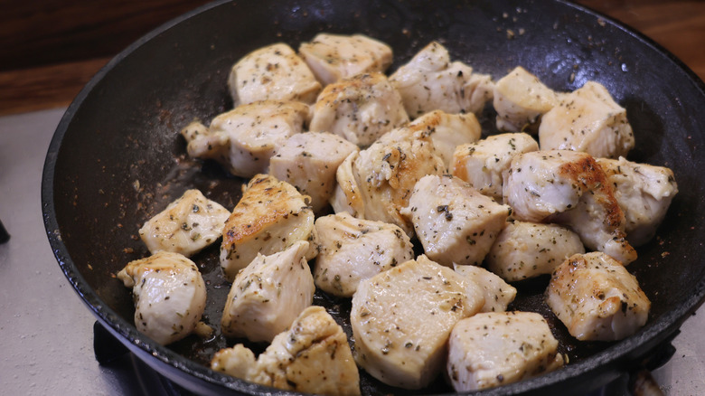 skillet full of cooked, seasoned chicken breast cubes