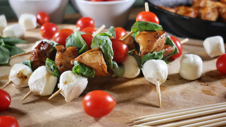 Margherita chicken skewers on wooden cutting board