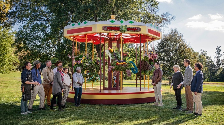 Clipped contestants and judges in front of topiary carosel