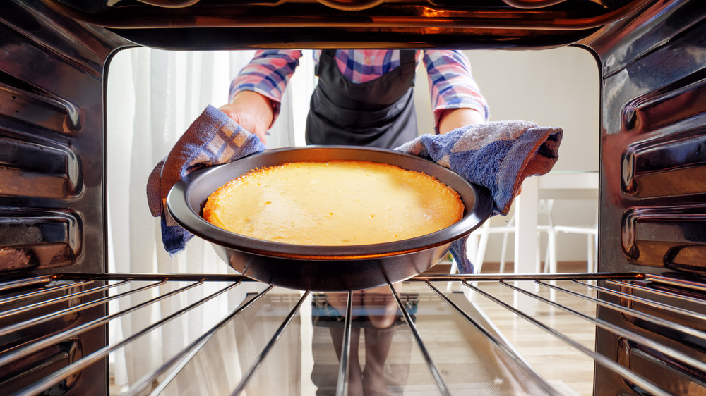 Person putting a cake in the oven