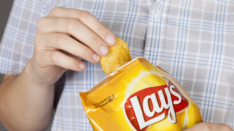 Hand holding bag of Lay's potato chips