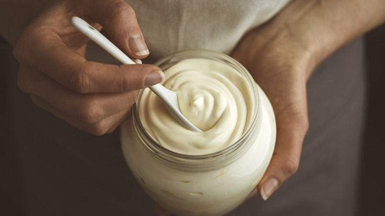 Man's hand squeezing bottle of mayonnaise