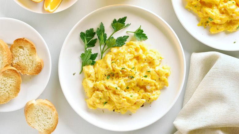 Scrambled eggs on white plate with parsley