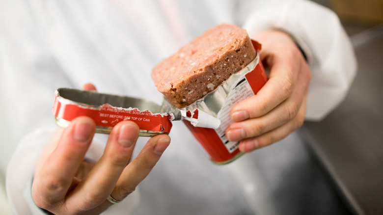 person holding corned beef can